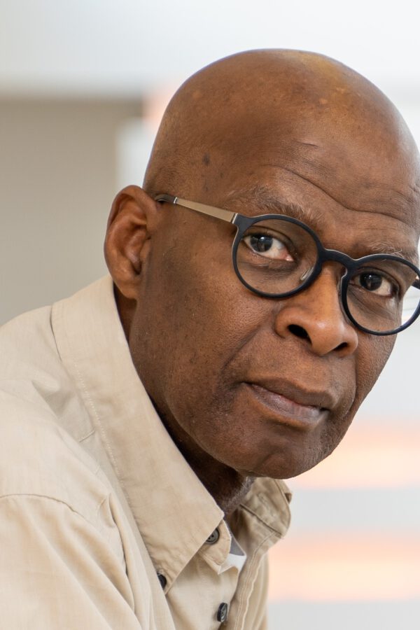 Person wearing glasses and a beige shirt, photographed indoors against a blurred background.