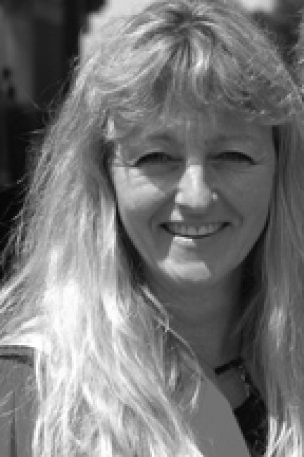 Black and white portrait of a person with long hair, smiling at the camera.