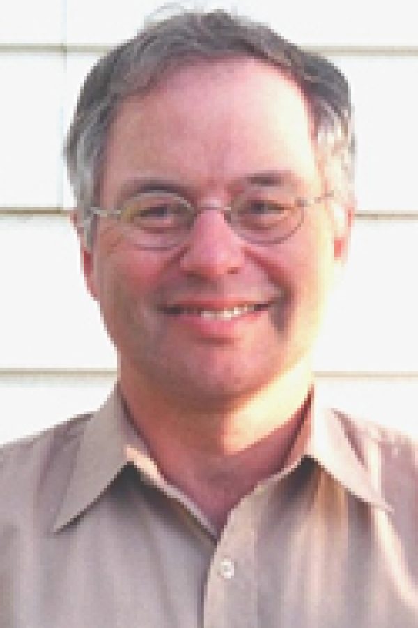 Smiling person with glasses wearing a pink shirt against a white background.