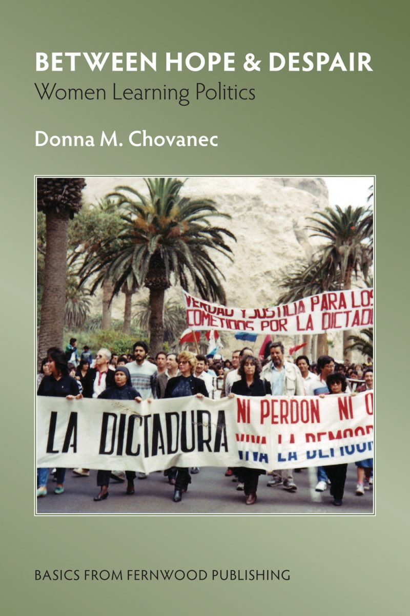 Protest march with people holding banners about dictatorship and democracy in Spanish, with palm trees in background.