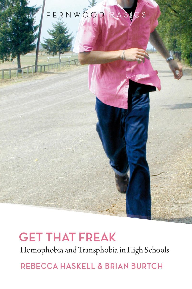 Person jogging on a rural road wearing a pink shirt and dark jeans, with trees visible in the background.