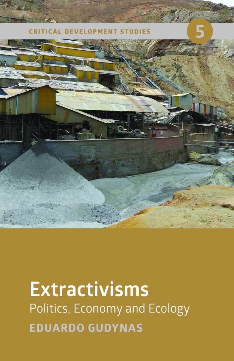 Industrial mining operation with yellow machinery and processing tanks beside a river in a mountainous area.