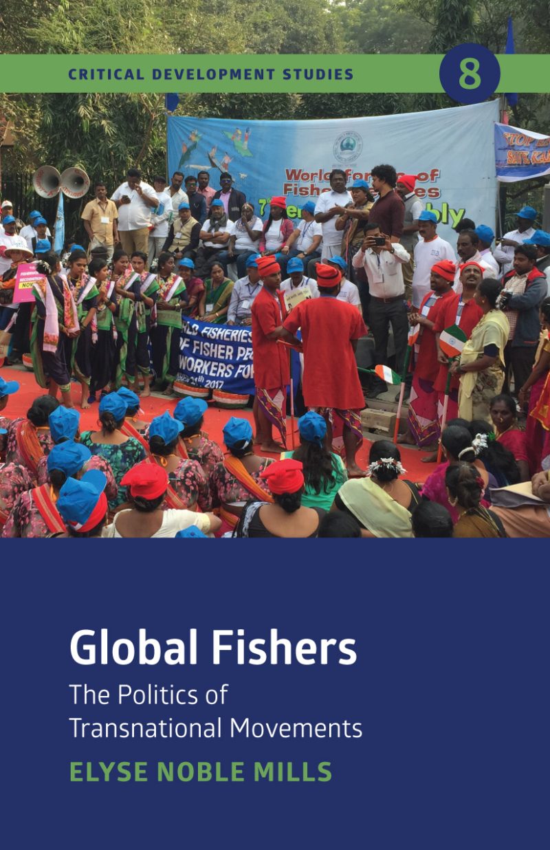 Large outdoor gathering of fishery workers wearing red and blue caps at a World Fisheries Day event with banner and stage.