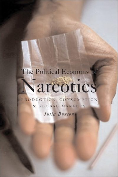 Hand holding plastic bags of drugs with book cover titled "The Political Economy of Narcotics" by Julia Buxton.