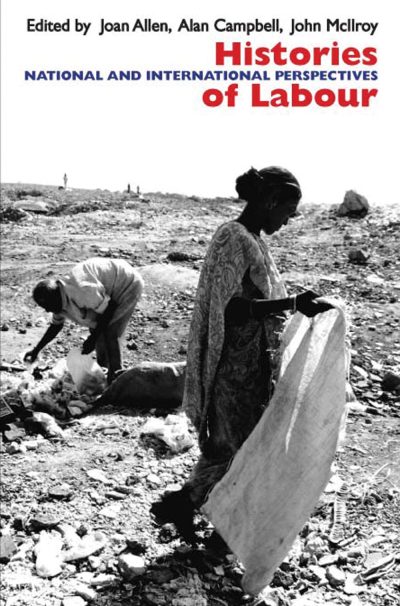 Black and white photograph of two people doing manual labor on rocky ground, holding fabric or cloth material.