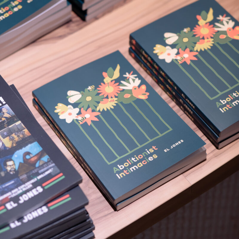 Stacks of books with dark blue covers featuring colorful floral designs arranged on a wooden surface.